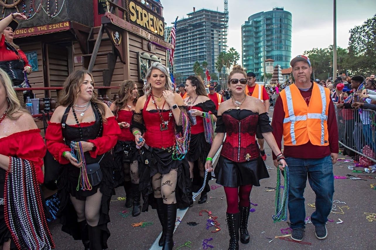 Parade participants in festive attire and beads.