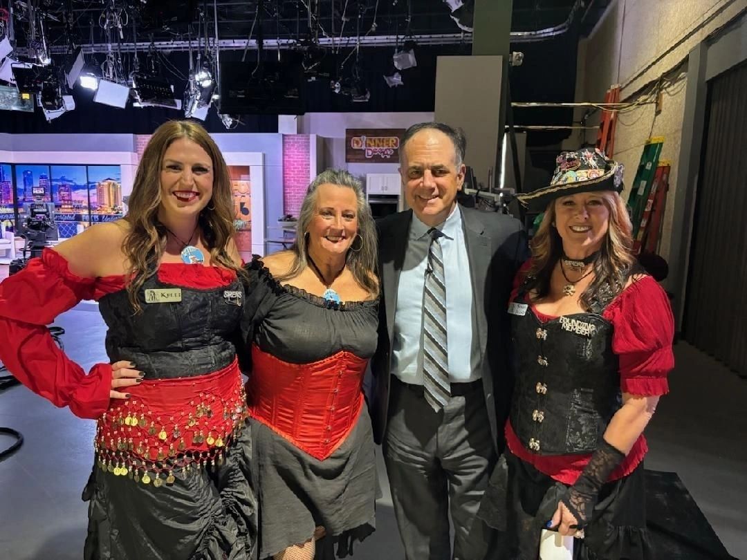 Four people smiling in studio, themed attire.